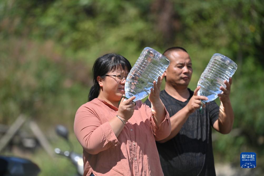 楊寧（左）在查看村民剛剛采集的水樣，為山泉水引水工程做準(zhǔn)備（10月8日攝）。新華社記者 黃孝邦 攝